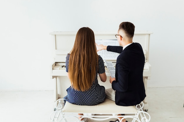 Vista trasera del joven enseñando a su novia piano
