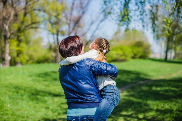 Vista trasera de madre con su hija en el parque