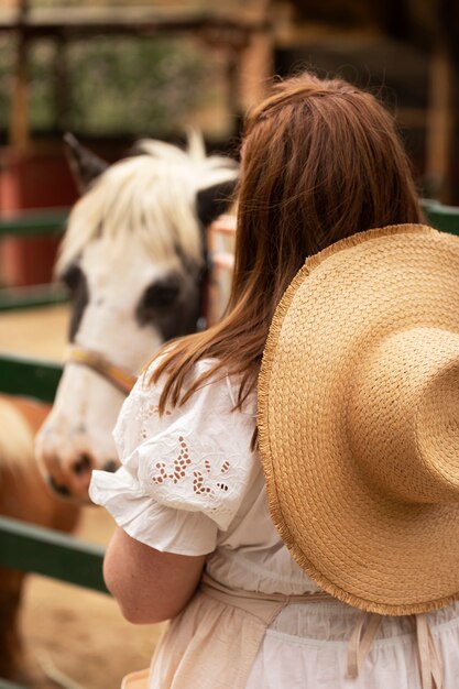 Vista trasera mujer cerca de lindo caballo