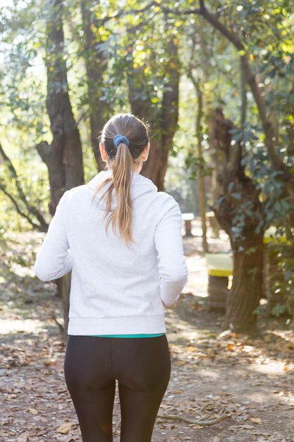 Vista trasera de mujer con coleta corriendo en el parque