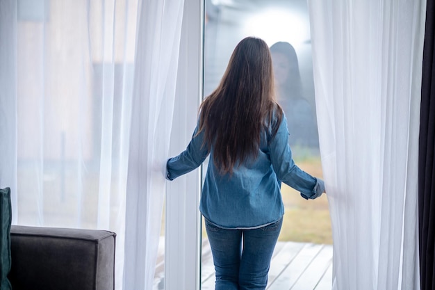 Foto gratuita vista trasera, de, mujer estar de pie, cerca, puerta de cristal