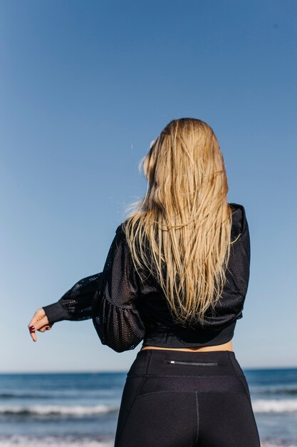 Vista trasera de mujer estirando en la playa