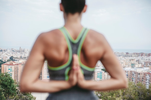 Vista trasera de mujer haciendo ejercicio de meditación enfrente de ciudad