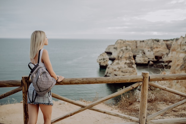 Foto gratuita vista trasera de la mujer joven con mochila viajero en el horizonte de paisaje marino de playa de fondo.