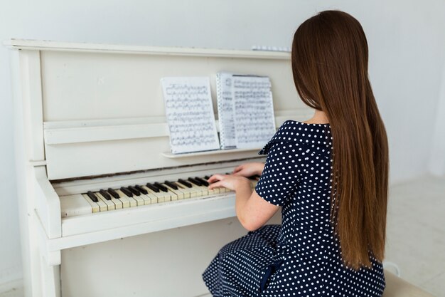 Vista trasera, de, mujer joven, con, pelo largo, tocar el piano