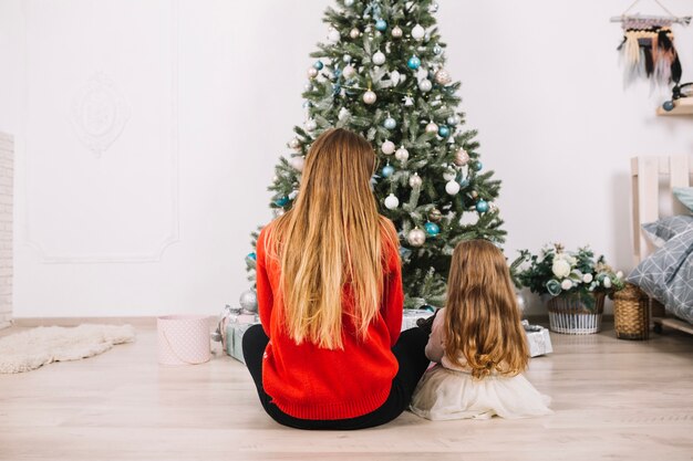 Vista trasera de mujer y niña celebrando navidad en casa