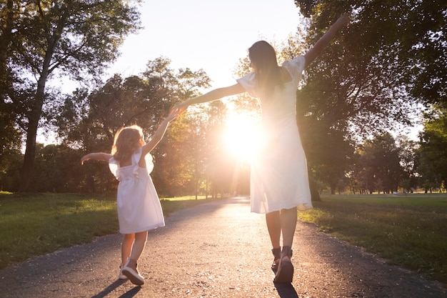 Foto gratuita vista trasera mujer y niña tomados de la mano