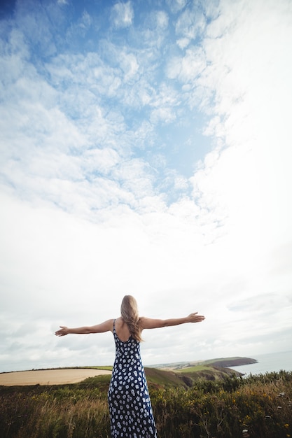 Foto gratuita vista trasera mujer de pie con los brazos extendidos