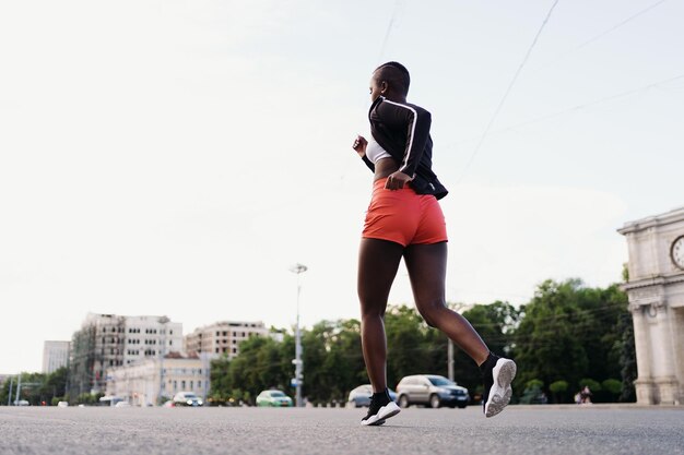 Vista trasera de una mujer en ropa deportiva corriendo en la ciudad hablando de una mujer multiétnica haciendo ejercicio físico