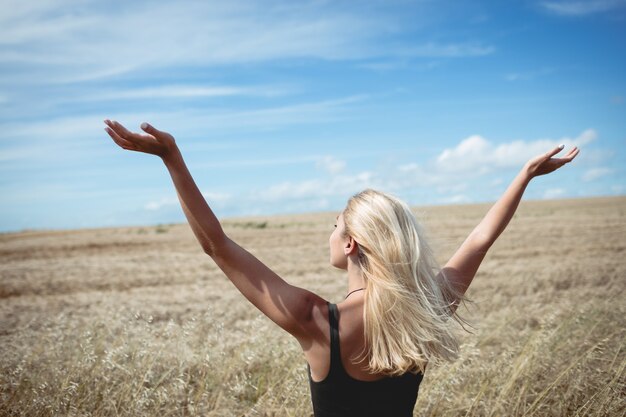 Vista trasera de la mujer rubia de pie en el campo