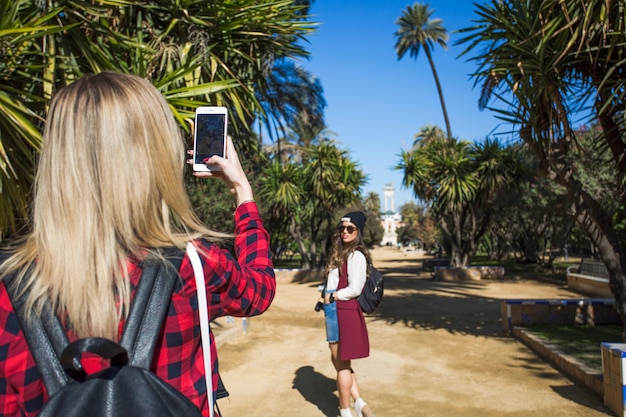 Vista trasera de una mujer tomando fotos de un amigo