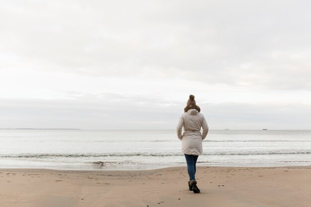 Vista trasera de la mujer walkingon shore