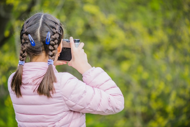 Vista trasera de niña con cámara y fondo borroso