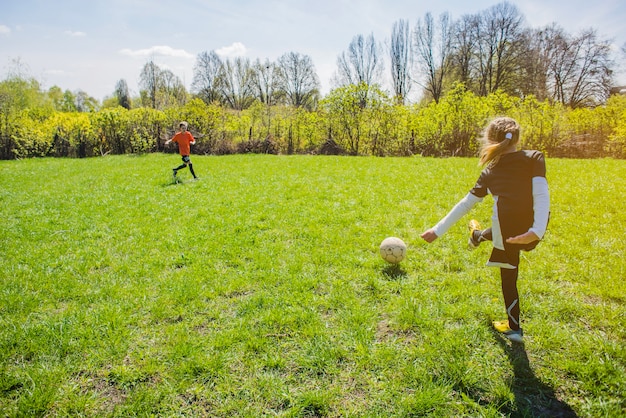 Vista trasera de niña golpeando el balón