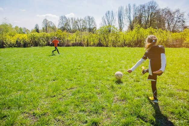 Vista trasera de niña golpeando el balón