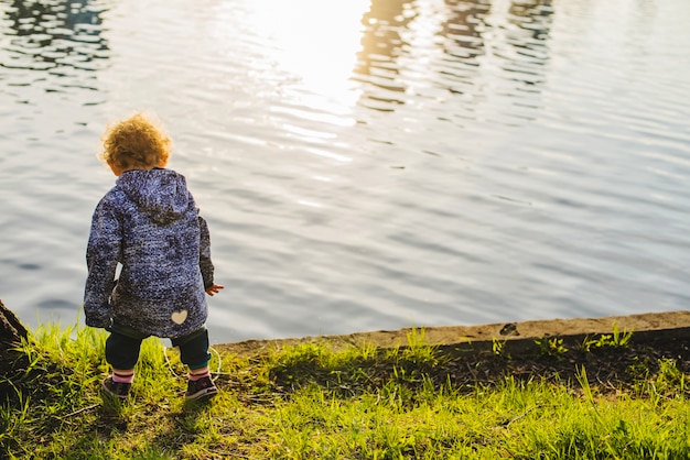 Foto gratuita vista trasera de niño jugando junto al lago