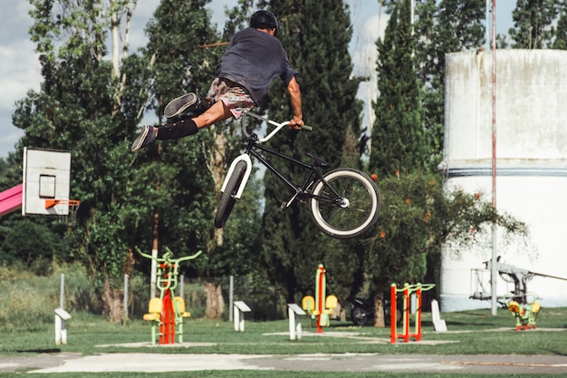 Foto gratuita vista trasera del niño con truco de bicicleta increíble en skate park