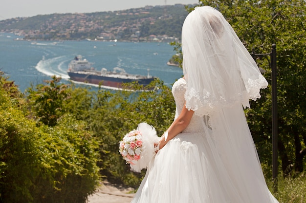 Vista trasera de novia con ramo mirando la bahía