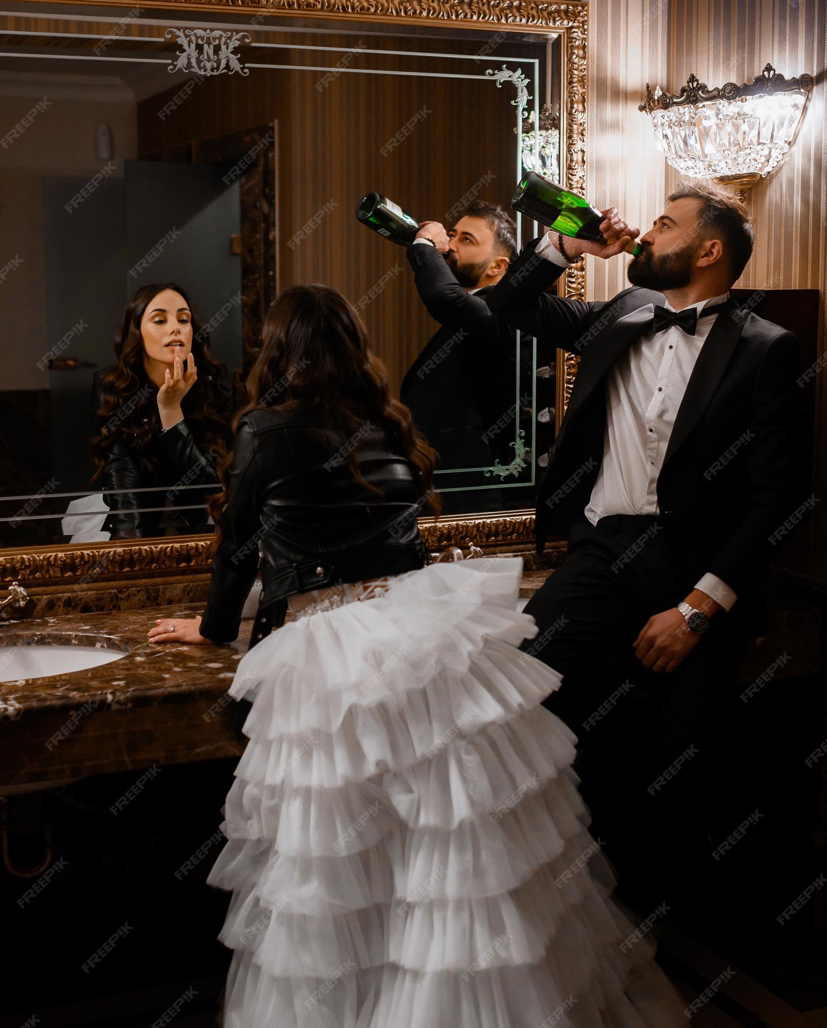 Vista trasera de la novia con vestidos de novia con volantes escalonados y chaqueta negra de cuero apoyada en el lavabo y tocándose los labios mientras | Foto Gratis Vista trasera de la novia con vestidos de novia con volantes escalonados y chaqueta negra de cuero apoyada en el lavabo y tocándose los labios mientras | Foto Gratis