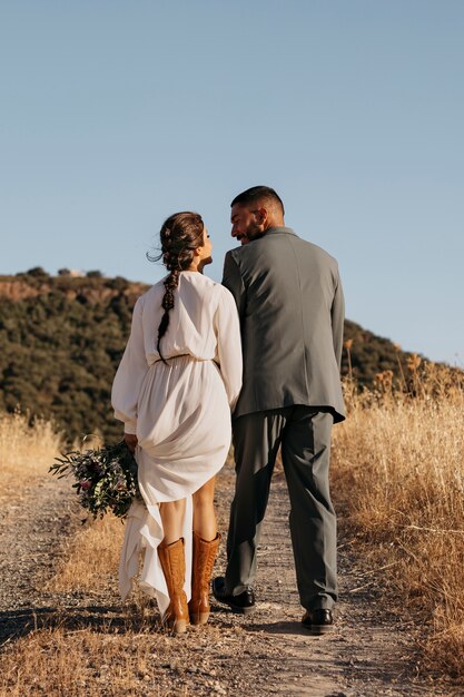 Vista trasera pareja casada tomados de la mano