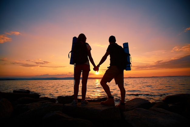 Vista trasera de pareja disfrutando de la puesta de sol