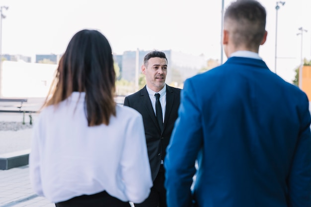 Vista trasera de pareja de negocios hablando con hombre de negocios