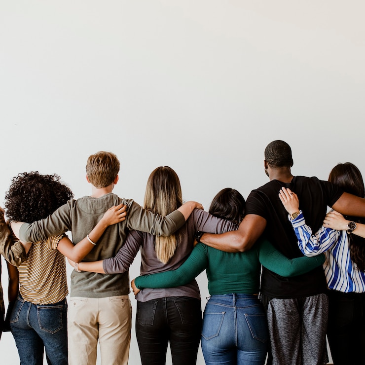 Vista trasera de personas diversas abrazándose unas a otras