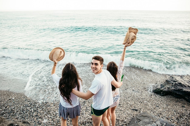 Foto gratuita vista trasera de tres amigos en la playa