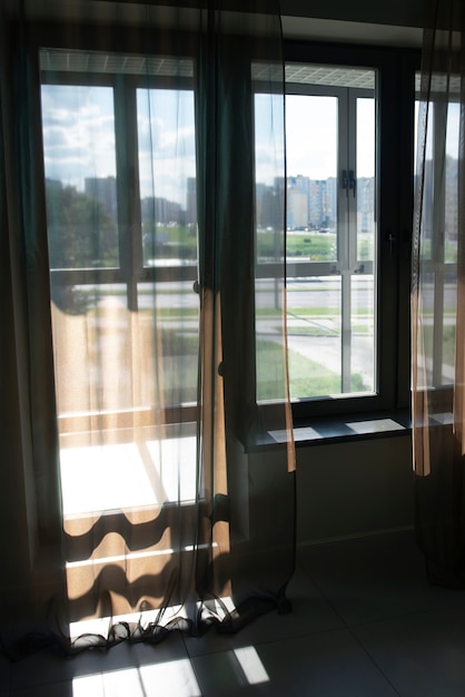 Vista de ventana con cortinas textiles y sombras.