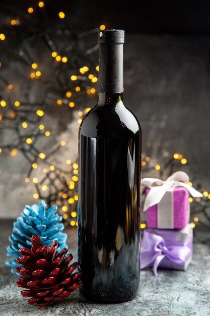Vista vertical de la botella de vino tinto para celebración y accesorios de decoración de regalos sobre fondo gris
