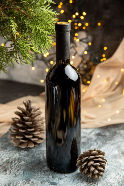 Vista vertical de la botella de vino de vidrio tinto para la celebración familiar y conos de coníferas de rama de abeto