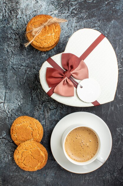 Vista vertical de la caja de regalo y galletas una taza de café sobre fondo oscuro helado