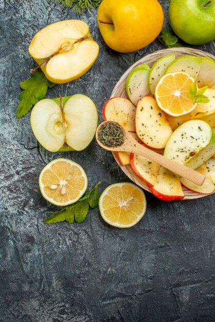 Vista vertical de la colección de frutas frescas orgánicas naturales en un plato blanco cubiertos con limones canela en el lado izquierdo sobre un fondo oscuro