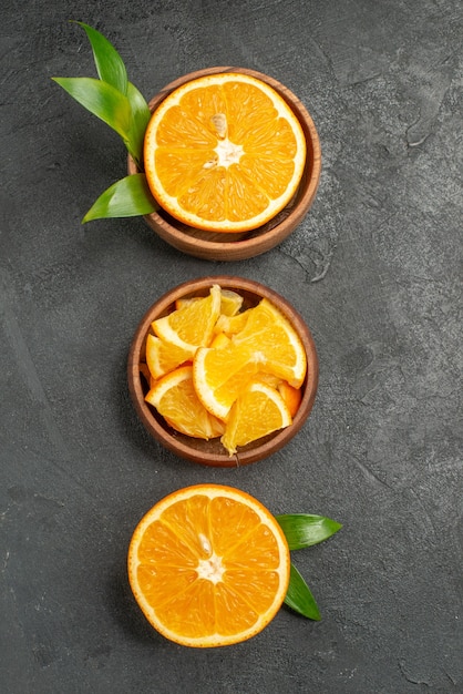 Foto gratuita vista vertical de cortar por la mitad en rodajas en trozos de hojas y flores de limones frescos en el cuadro negro