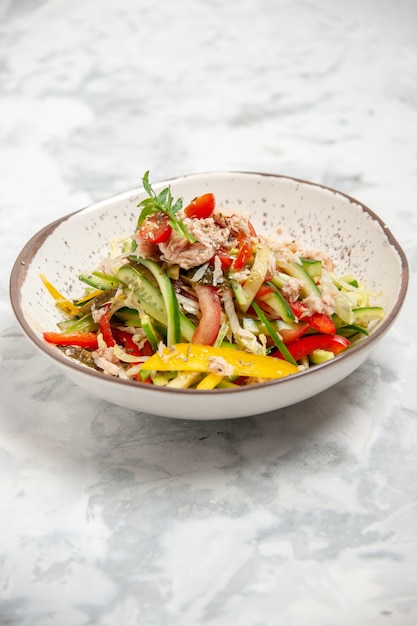 Vista vertical de una deliciosa ensalada de pollo con verduras en la superficie blanca manchada