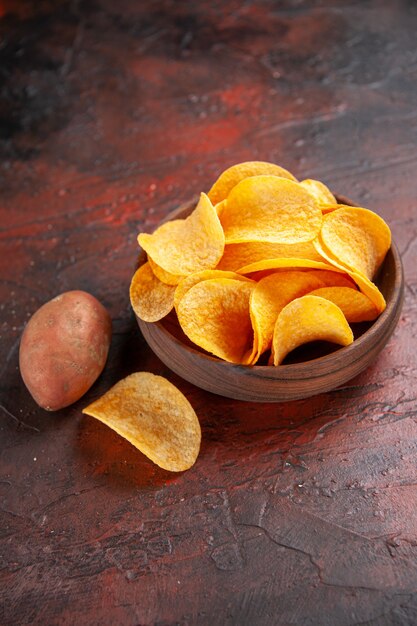 Vista vertical de deliciosas patatas fritas crujientes caseras en un pequeño recipiente marrón en el lado izquierdo del fondo oscuro