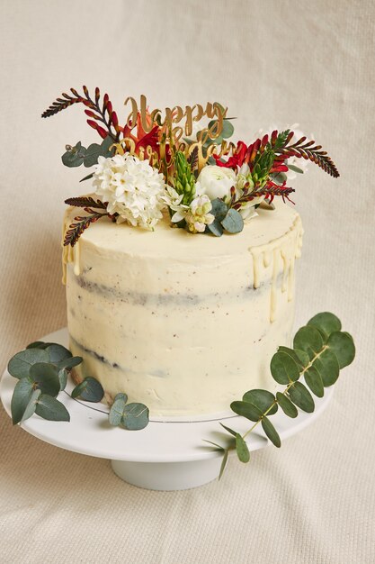Vista vertical de un delicioso cumpleaños crema de flores blancas en la parte superior del pastel con un goteo en el lateral