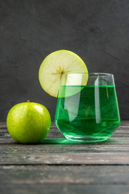 Vista vertical de delicioso jugo natural fresco en un vaso y manzanas verdes sobre fondo negro