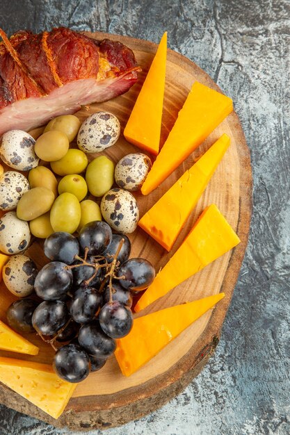 Vista vertical de un delicioso refrigerio que incluye frutas y alimentos para el vino en una bandeja marrón sobre fondo gris