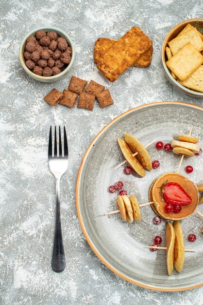 Vista vertical de deliciosos panqueques con chocolate y galletas sobre fondo azul