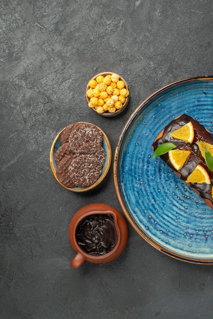 Vista vertical de deliciosos pasteles en bandeja azul y galletas sobre fondo oscuro