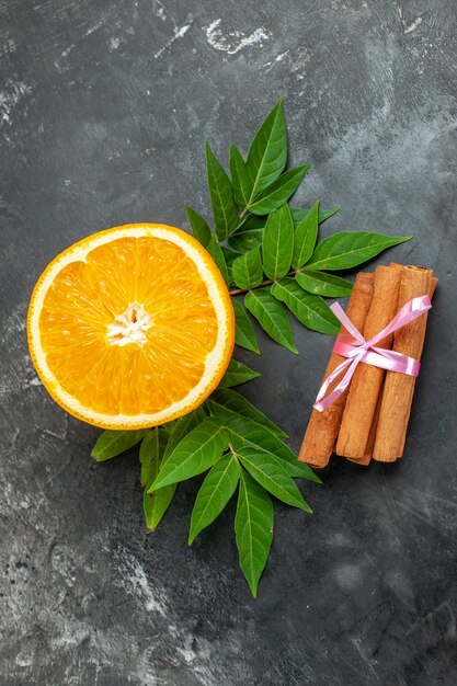 Vista vertical de la fuente de vitamina naranjas frescas naturales con hojas de limón canela sobre fondo gris