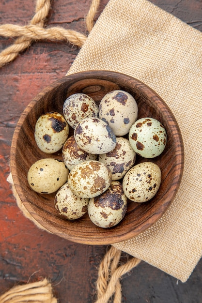 Vista vertical de huevos de granja avícola orgánicos frescos en un recipiente de madera sobre un fondo marrón