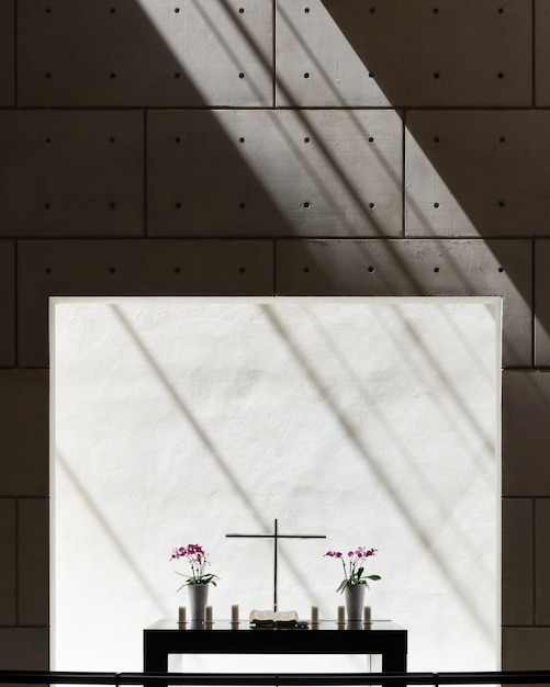 Foto gratuita vista vertical de los jarrones y una cruz en una mesa en una habitación con muro de hormigón