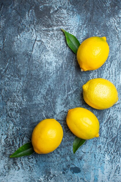 Vista vertical de limones frescos naturales orgánicos con hojas sobre fondo oscuro