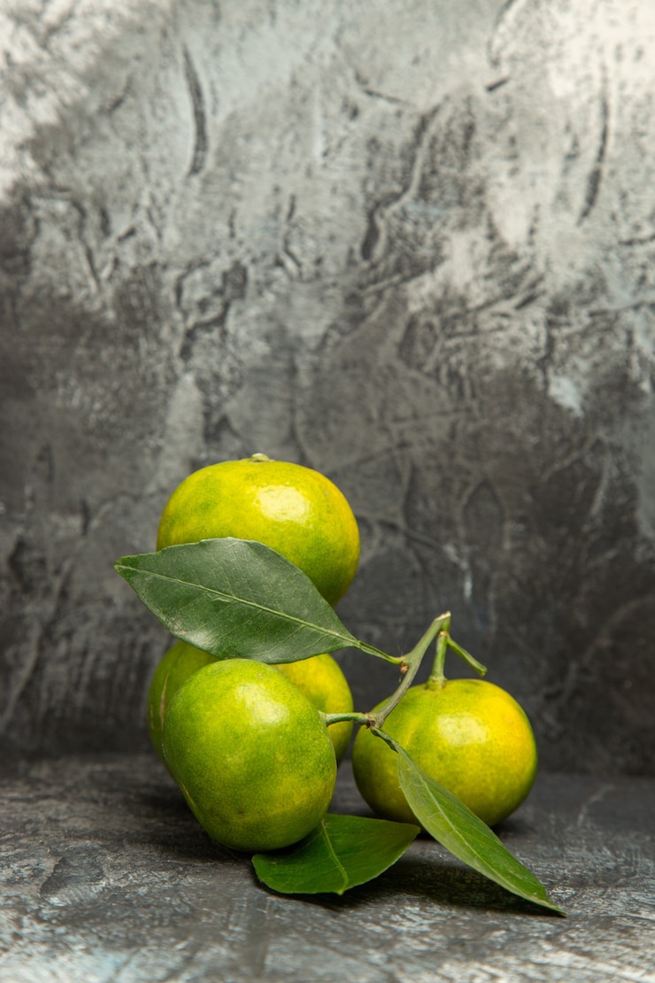 Foto gratuito vista vertical de mandarinas verdes frescas con hojas en imágenes de fondo gris