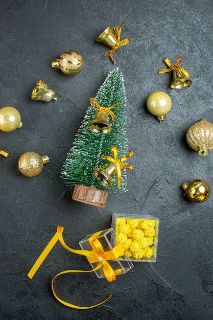 Vista vertical de la mano que sostiene las cajas de regalo de accesorios de decoración y árbol de navidad sobre fondo oscuro