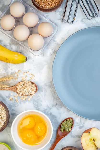 Vista vertical del plato vacío y los ingredientes para los alimentos saludables sobre fondo azul blanco