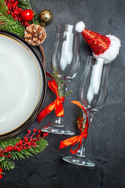 Foto gratuita vista vertical de platos de cena accesorios de decoración ramas de abeto calcetín de navidad copas de vidrio sobre mesa oscura