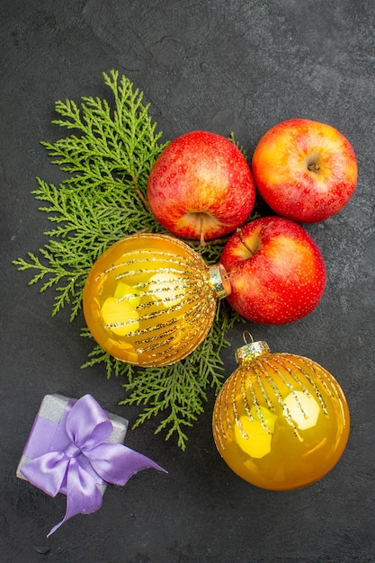 Foto gratuita vista vertical de regalos y manzanas frescas orgánicas naturales y accesorios de decoración sobre fondo negro
